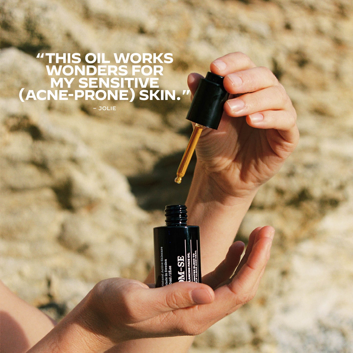 Hand holding a dropper over a bottle of OM-SE Balancing Face Oil.